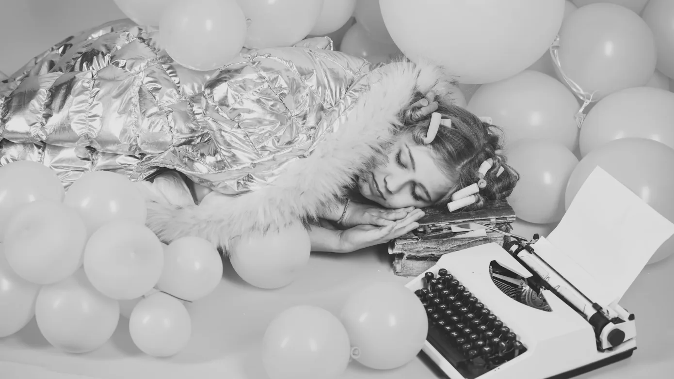 woman sleeping next to typewriter implicating that it's hard to write content